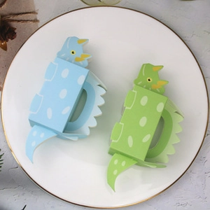 Detail view of 3D dinosaur shaped gift boxes in blue and green on a ceramic tray