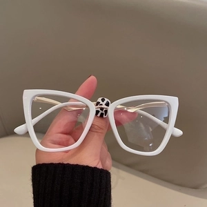 Detailed view of white cat-eye glasses frame featuring unique cow print pattern on bridge