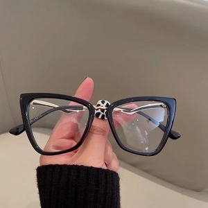 Detail of black cat-eye glasses frame featuring gold wavy metal temples and model 40-142 CE