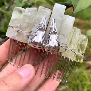 Detail view of natural crystal columns and silver skull charms on a handmade hair comb