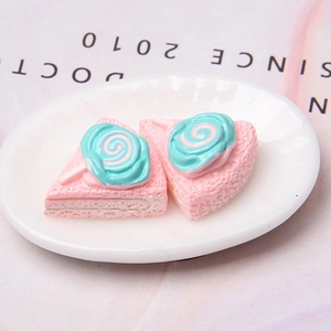 Macro detail of miniature resin cake model on a tray with pink and teal cream accents