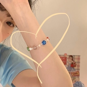 Detalle de pulsera de perlas con pétalos de flores de acrílico de colores en la muñeca