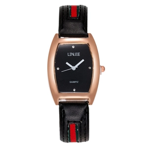Detail of rose gold tonneau watch case with black dial and signature striped leather band