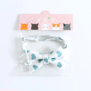 Close-up of white pet bow collar with blue heart patterns in original packaging