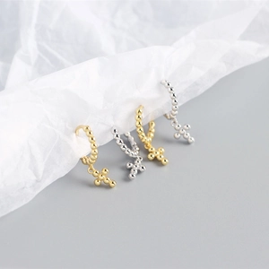 Detailed view of geometric beaded cross hoop earrings in gold and silver finishes