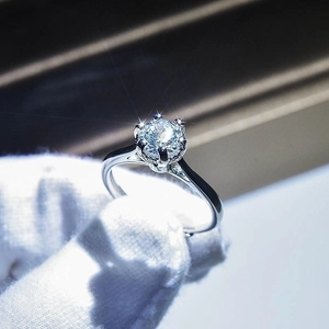 Macro shot of a brilliant moissanite ring with classic six-prong setting on a gloved finger
