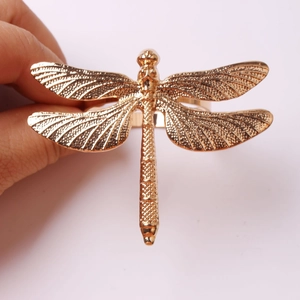 Golden dragonfly napkin ring with intricate mesh wings shown in a hand-held view