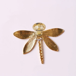 Macro view of golden dragonfly furniture handle showing detailed wing texture and base