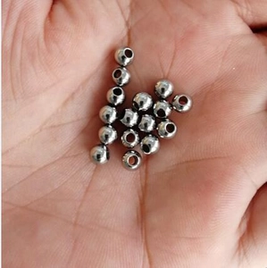 Gros plan de petites perles en acier inoxydable argenté sur une main pour l'échelle