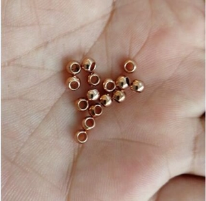 Détail de perles rondes en acier inoxydable or rose avec trou présentées dans la paume
