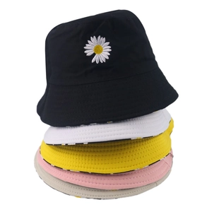 Stacked reversible daisy sun hats in black, white, yellow, pink, and beige cotton canvas