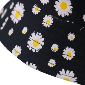 Close-up of small white daisy print and reinforced stitching on black cotton bucket hat