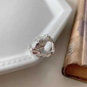 Macro view of silver 925 open ring with lava texture on a white decorative plate