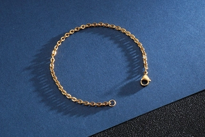 Detail of golden stainless steel cable chain bracelet featuring a secure lobster clasp