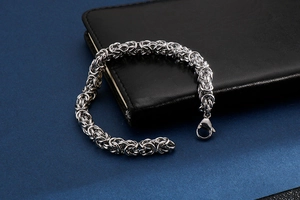 Macro shot of silver Byzantine chain bracelet with lobster clasp on dark background