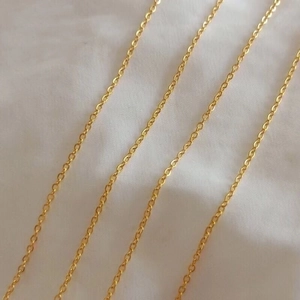 Classic gold titanium steel cable chain necklace laid on white fabric background
