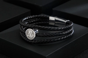 Close-up of triple-layer braided leather bracelet with silver '忍' engraved charm