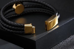 Macro shot of gold magnetic clasp on multi-layer black braided leather bracelet