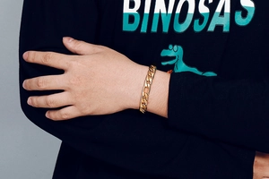Gros plan d'un gros bracelet à maillons cubains dorés au poignet pour un look très stylé