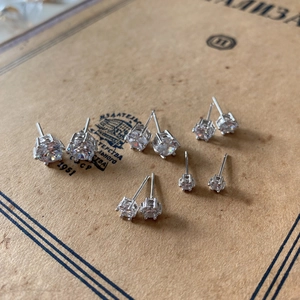 Macro shot of 925 sterling silver six-prong cubic zirconia stud earrings set on vintage paper