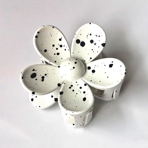 Macro view of white flower hair claw clip with artistic black ink splash pattern