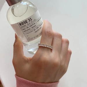 Close-up of gold band ring with rectangle cut zircons worn while holding a perfume bottle