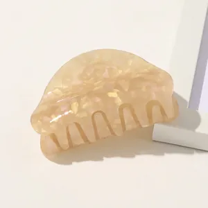 Detail of cream acetate hair claw clip with marble texture and gold glitter sparkles