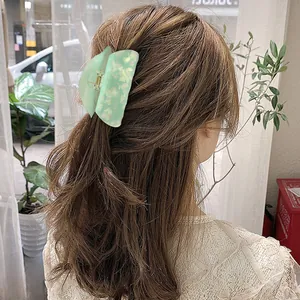 Mint green acetate shark hair claw with marble texture shown on woman long hair