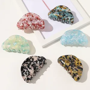 Close-up of six acetate hair claws in marble and amber patterns on a clean white surface