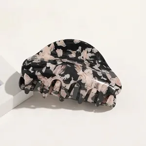 Macro view of a large black and white marble acetate hair claw clip with glossy finish