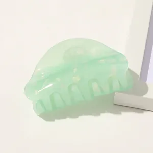 Macro detail of a pearlescent mint green acetate hair claw clip for elegant hairstyling