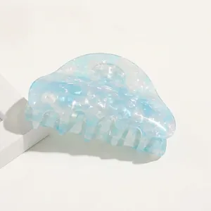 Macro detail of large acetate hair claw clip featuring blue and white marble texture