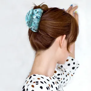 Detail showing marble texture acetate shark hair claw clip holding a low bun hairstyle