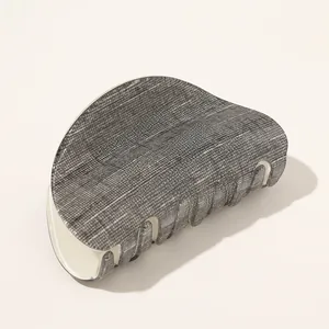 Detail view of large gray hair claw clip with fabric-like texture and cream teeth