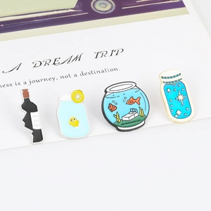 Detailed close-up of four artistic blue cartoon enamel brooches on a white display card