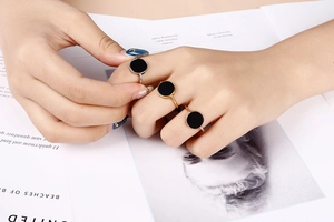Detail of 18k gold plated stainless steel rings shown on hand over a magazine background