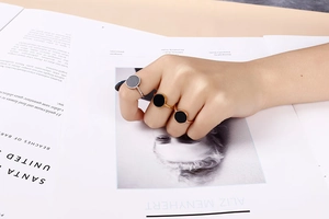 Close-up of gold and silver minimalist rings with black agate inlay on a model's hand