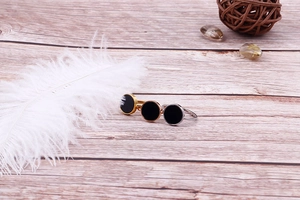 Three-color 18k gold-plated stainless steel rings with black circular inlay on wood surface