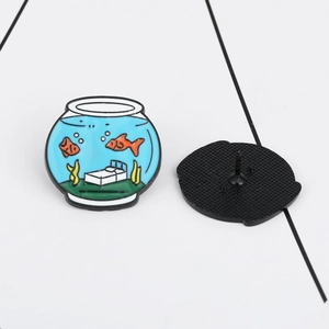 Detail view of cartoon fishbowl enamel pin and black rubber clutch back on white background