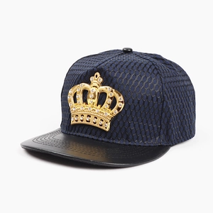 Detail of a dark blue mesh hip hop cap with golden crown emblem and black leather brim