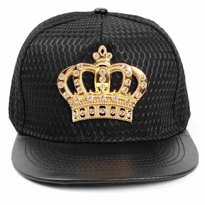 Detail of a hip-hop cap featuring a gold crown emblem with rhinestones and snake texture