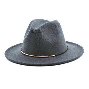 Détail d'un chapeau fedora gris foncé avec ruban noir et ornement métallique doré chic