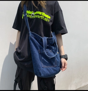Close-up of deep blue denim tote bag with wide shoulder strap and front pocket detail