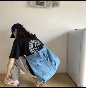 Detail of blue denim tote bag showing stitching and side pocket in casual urban style