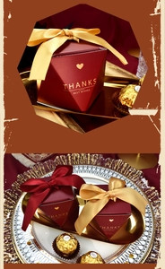 Close-up of elegant burgundy geometric wedding candy box with gold ribbon and foil lettering