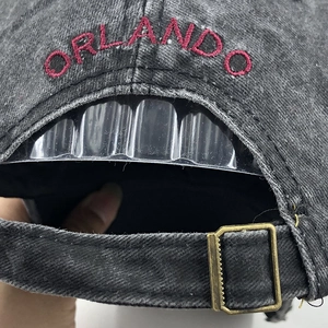 Detail of red Orlando embroidery and bronze metal buckle on washed cotton baseball cap