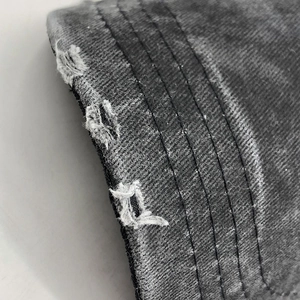 Macro detail of distressed cotton fabric with reinforced stitching on a baseball cap brim