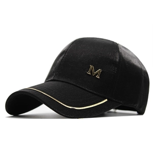 Detail view of black satin baseball cap featuring gold metal M logo and brim stripes