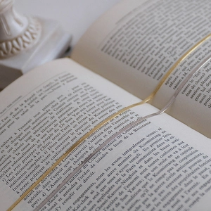 Flat lay of gold, silver, and rose gold snake chain necklaces used as bookmarks on a book