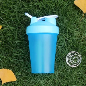Close-up of blue fitness shaker bottle with a stainless steel whisk ball on grass